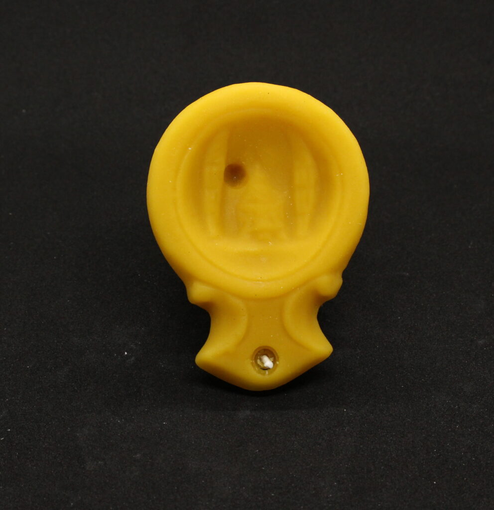 A handheld yellow beeswax Oil lamp candle against a charcoal background.