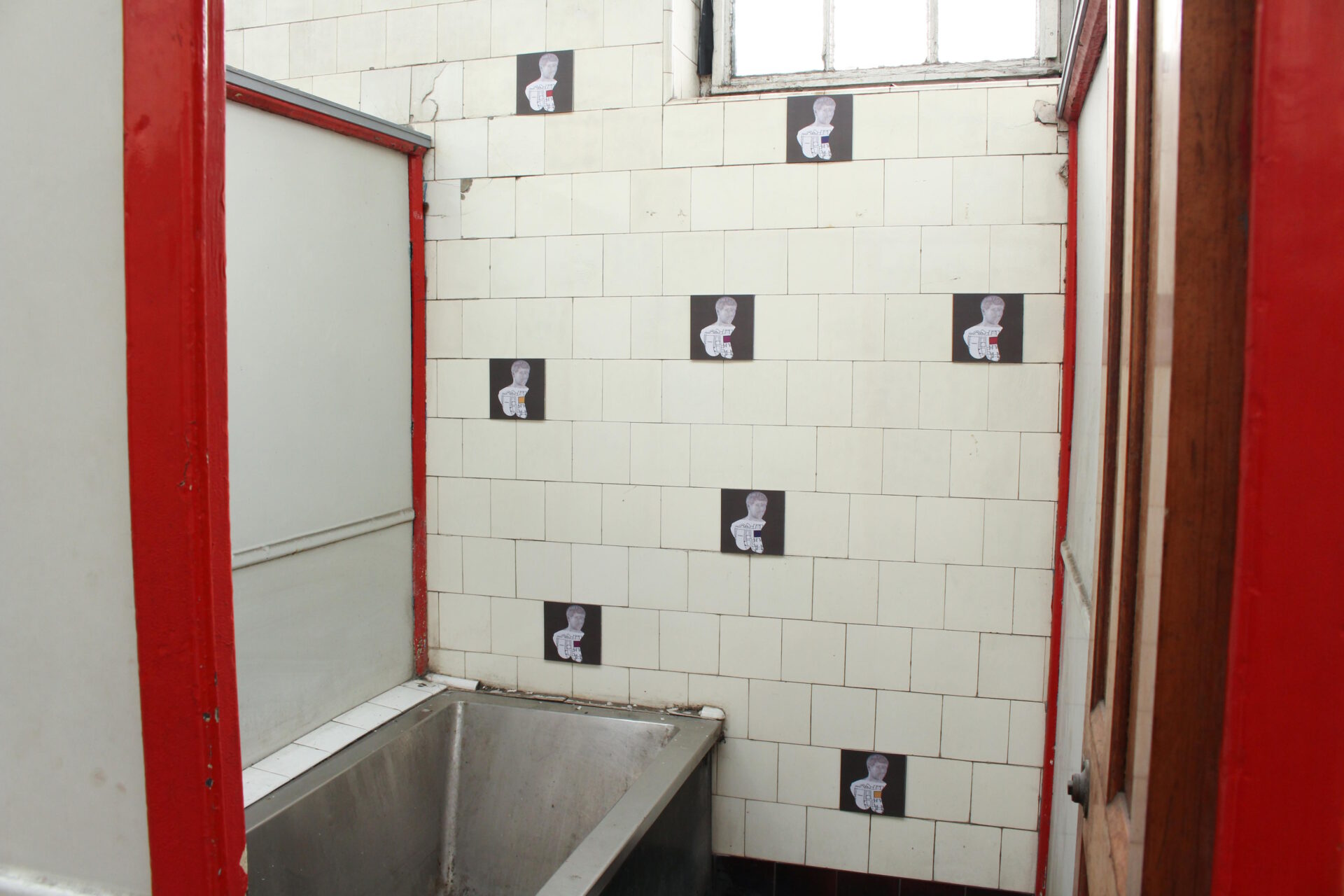 Eight digital tiles featuring Trajan are positioned randomly inside a red and cream swimming pool cubicle with a bath.