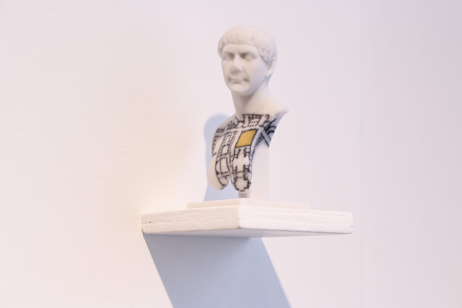 White 3D print of Trajan on a shelf with dimensions of a thermae in black with a yellow square to represent the location.