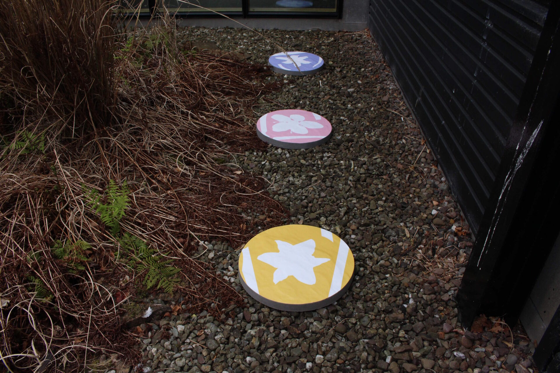 Three circular slabs with an outdoor graphic on each one, including yellow, pink and blue of a white daffodil, cherry blossom and bluebell petal separately.